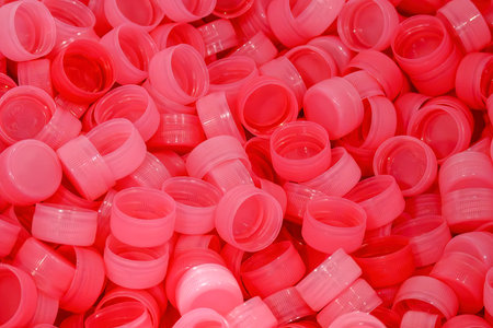 The pile of red plastic caps of drinking water bottles. The plastic caps manufacturing concept.の写真素材