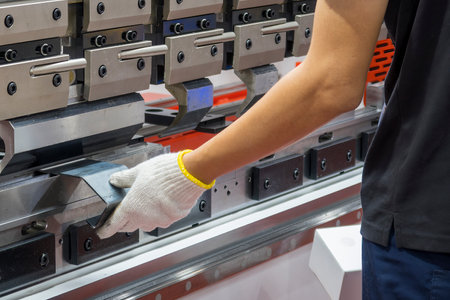 Close up the bending machine operator hold the sheet metal parts with safety glove. The sheet metal...