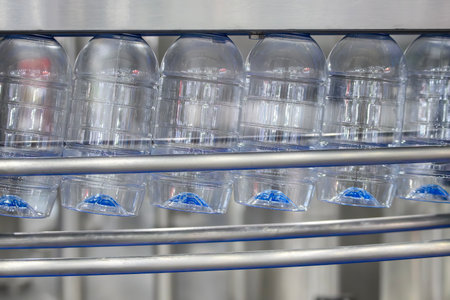 The  empty drinking water bottles  hanging on the conveyor belt for filling process. The hi-technology of drinking water manufacturing process.の写真素材