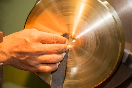 Closeup scene the lathe machine operator polishing the brass material parts by sand paper. The metalworking process by turning machine.の写真素材