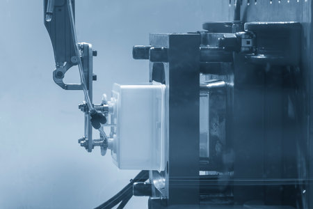 Close up scene material handling process the food container by robotic system from injection machine.  The food container production process by automatic system from plastic injection mold machine.の写真素材