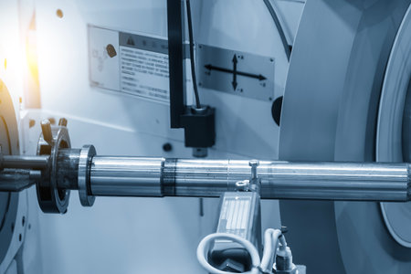 The operation of cylindrical surface grinding machine with the metal shaft parts in the light blue scene. The surface finishing process by grinding machine.の写真素材