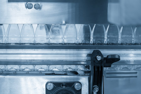 The  empty drinking water bottles  hanging on the overhead conveyor belt for filling process. The hi-technology of drinking water manufacturing process.の写真素材
