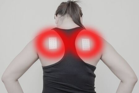 Women Neck, shoulder pain and sticking plaster.Concept photo with Color Enhanced pale skin with read spot indicating location of the pain.の写真素材