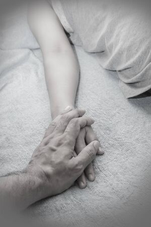 Hold patient's hand in bed.black and white picture.Conception of illnessの写真素材