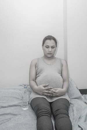Pregnant woman on bed black and white picture.Conception of illnessの写真素材