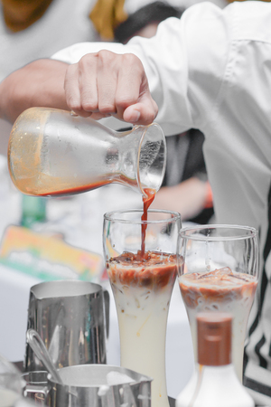 Barista making a cup of coffee.Batista poured coffee on a milk cream bubble.の写真素材