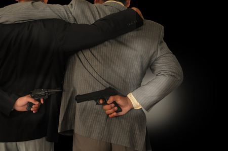Behind the two businessmen holding a gun,Concepcion dishonesty in business.の写真素材