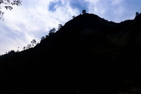 blue clouds on the background with a mountain in front. silhouetteの写真素材