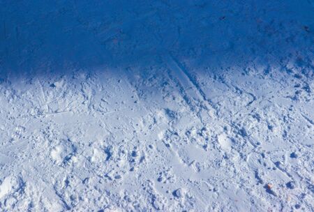 snow-covered land with half in shadow and other half-lit with sunlightの写真素材