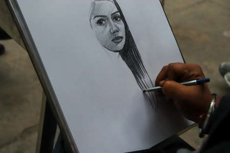 01 Janurary â2019, Rock Garden, Chandigarh, Punjab. A person drawing a sketch of girl on white paper with a pencil on white paper at Rock Garden, Chandigarh, Punjab, Indiaのeditorial素材