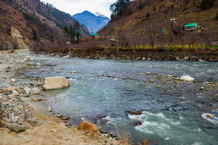 A river flowing on the side of road and mountain have rocks in the riverの写真素材