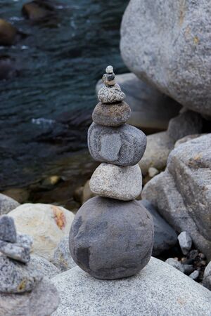 Rock Balancing: Stone Stacking Art having flowing river in the backgroundの写真素材