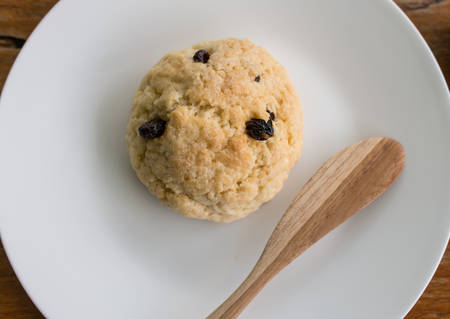 peice of blueberry scone on white plate and wodden spoonの写真素材