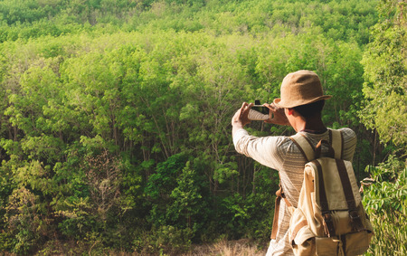 A man with backpack taking photo.Travel Lifestyle wanderlust adventure concept summer vacations outdoor alone into the wildの写真素材