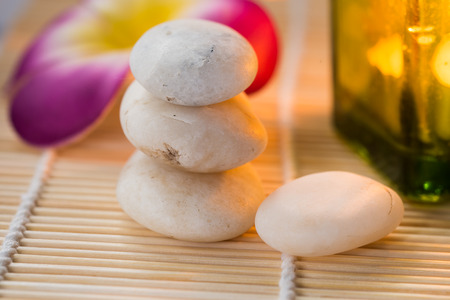 Candle and white stones with flower on bamboo matの写真素材