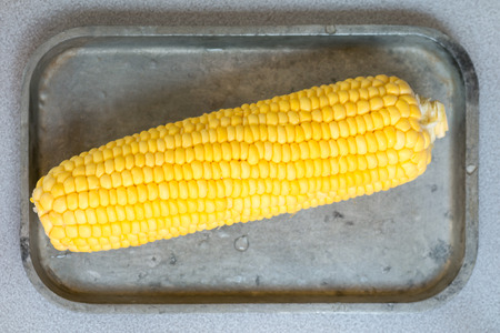 A yellow boiled corn on metal plateの写真素材