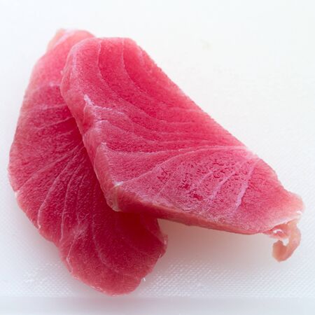 Closeup pieces of tuna fillet on white cutting boardの写真素材