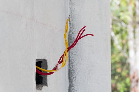 Unfinished electric cale on concrete wall in construction siteの写真素材