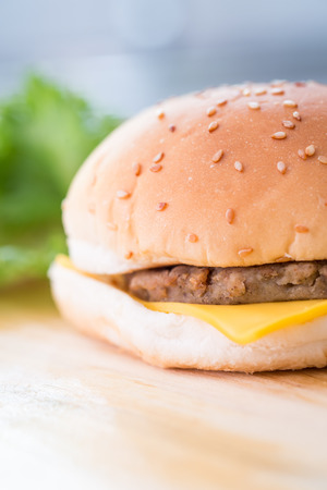 Closeup of a cheese burger on a wooden plateの写真素材