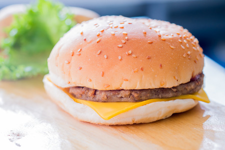 Closeup of a cheese burger on a wooden plateの写真素材