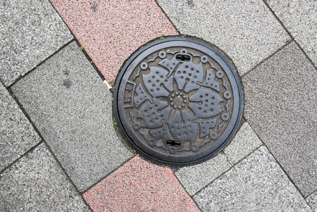 Manhole cover in Tokyo, Japan. With ginkgo leaves and sakura flower on a manholeの写真素材