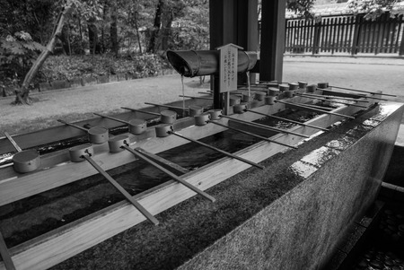 Tokyo, Japan - November 30, 2015: Black and white photo of A purification trough by the entrance to the Meiji Shrine in Tokyo. Shinto observers use it to wash their hands and mouths before entering the shrine.のeditorial素材