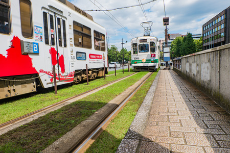 KUMAMOTO, JAPAN - SEPTEMBER 27, 2014: Classic tram of Kumamoto city at the tram stop near Kumamoto castle in Kumamoto, Kyushu , Japan. Team is the easiest way to access tourist spot in Kumamoto city is by using local trams service.のeditorial素材