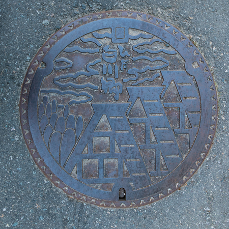 Shirakawa-go, Japan - May 2, 2016: Manhole cover of Shirakawago village, Gifu Prefecture, Japan. The Gassho Style houses engraved on to a manhole cover as a symbol of an important village's landmark.のeditorial素材