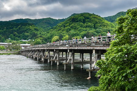 Kyoto, Japan - May 7, 2016: Togetsu-kyo Bridge in Arashiyama district, Kyoto, Japan. The Togetsu-kyo Bridge has been a landmark in Western Kyoto's Arashiyama District. The wooden bridge spans the Katsura River in front of Arashiyama Mountain, offering incのeditorial素材