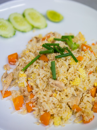 Chicken fried rice on white plate serve with lime and cucumberの写真素材