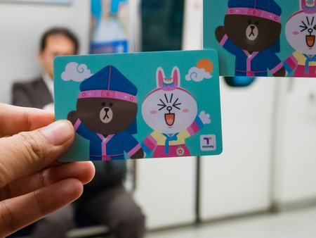 Seoul, South Korea - October 16, 2017: Hand holding T-Money card with Line characters in Subway at Incheon International Airport in  Seoul, South Korea.のeditorial素材