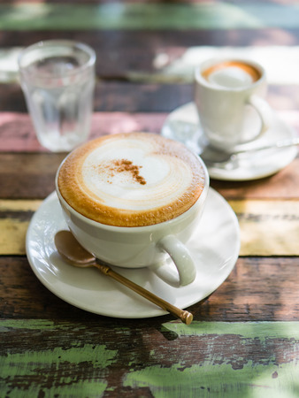 Cup of hot Cappuccino coffee close up on the wooden tableの写真素材