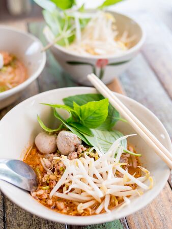 Thai food - Thai style spicy Tomyam noodle soup, famous Thai noodle soup on wooden table, selective focus.の写真素材