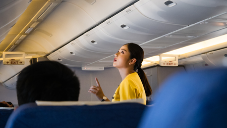 Bangkok, Thailand - October 29, 2018: A female flight attendant is assisting a passenger in the economy class of the route Bangkok - Tokyo of Nok scoot Airline.のeditorial素材