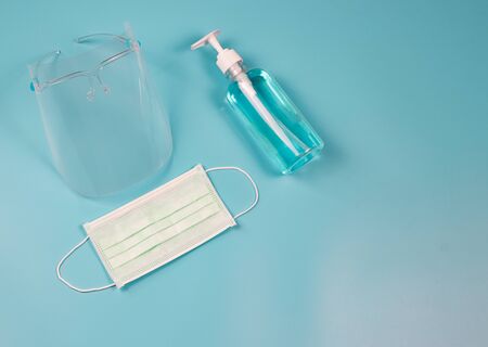 Coronavirus or COVID-19 prevention and new normal lifestyle concept. Top view of face shied  , alcohol hand sanitizer gel and surgical  face mask  on blue background.の写真素材