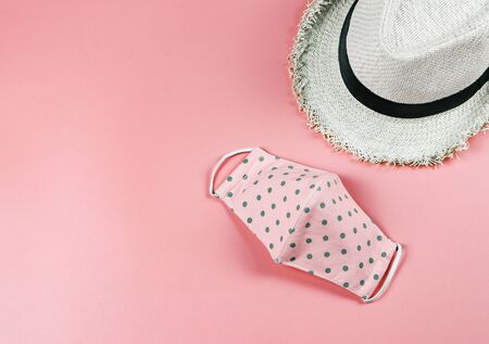 Coronavirus or COVID-19 prevention and new normal lifestyle concept. Top view of  pink polka dot  fabric face mask  and hat on pink background with copy space.の写真素材
