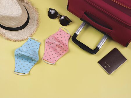 COVID-19 prevention while traveling and new normal lifestyle concept. Top view of  polka dot fabric face masks with passport and  travel accessories on yellow background with copy space.の写真素材