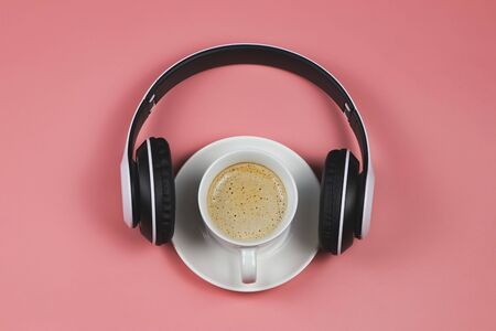 Top view or flat lay of headphones and coffee cup on pink background with copy space. Music and coffee time relaxing concept.の写真素材