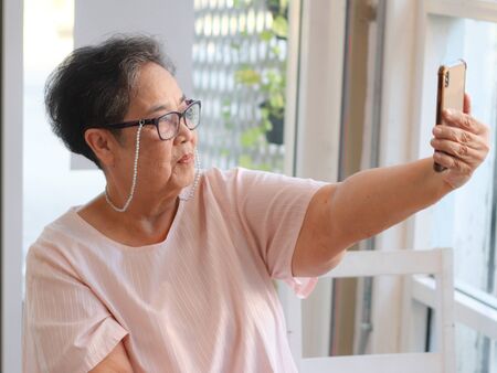 Active and happy senior woman selfie herself with mobile phone.の写真素材