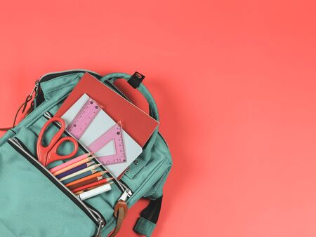 Back to school concept.Top view of green backpack with school supplies on red  background with copy space.の写真素材