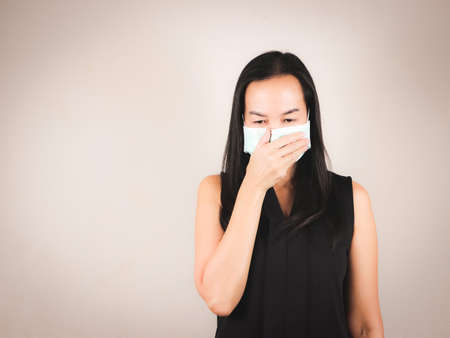Asian woman wearing hygienic mask on grey background with copy space ,daily protection from corona...