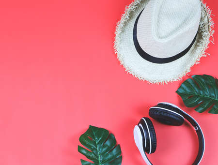 Music , travel and relaxation concept.Top view or flat lay of headphones, hat and tropical monstera leaves on red background with copy space.の写真素材