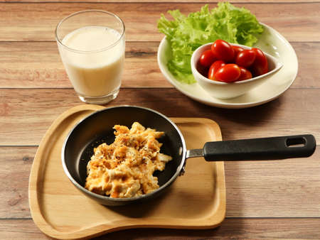 Top view of breakfast set , scramble eggs in pan , vegetable and tomato , and  milk  on wooden background.の写真素材