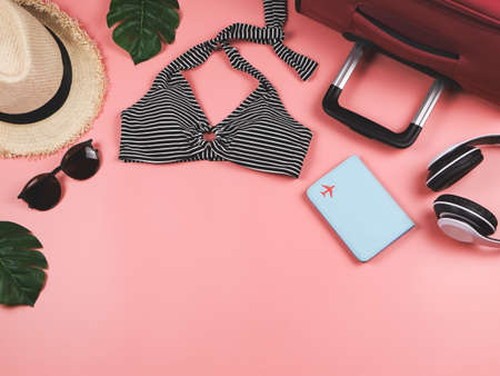 Travel and summer holiday concept, top view of  black and white stripe pattern  bikini swimsuit , passport and women's vacation accessories items  on pink background with tropical monstera leaves.の写真素材