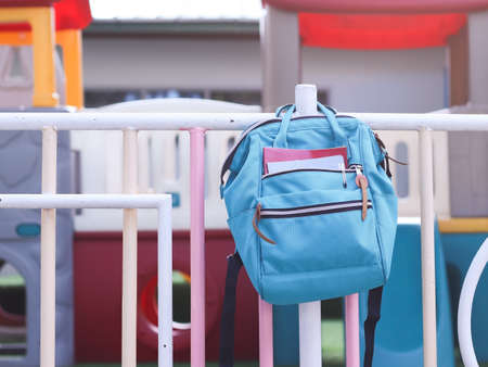 Education , back  to school  concept.School backpack haging on playground fence with playground...