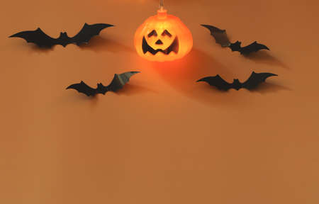 Top view of Halloween pumpkin light and black paper bats on orange background with copy space. Halloween  concept.の写真素材