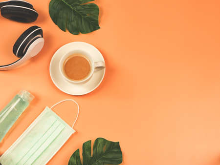 Top view or flat lay of coffee cup, headphones ,medical face mask and alcohol sanitizer gel on...