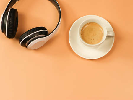 Top view or flat lay  of coffee up and headphones on orange background.minimal style.positive...
