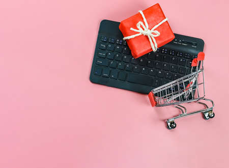 Top view or flat lay of computer keyboard , red gift box, shopping cart on pink background with copy space.  Seasonal  holiday and online shopping concept.の写真素材